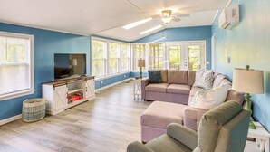 A spacious living room with a television, a sofa, and a ceiling fan.