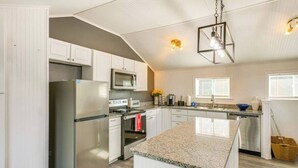A modern kitchen with stainless steel appliances, granite countertops, and a central island.