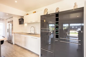 A modern kitchen with a stainless steel refrigerator, white cabinets, and a wooden countertop.