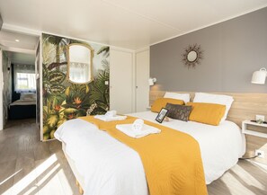 Een hotelkamer met een bed, een spiegel, een wandklok en een deur naar een andere kamer.