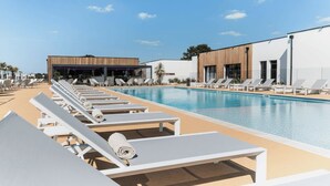 A pool area with lounge chairs and a building with a modern design. - Your dream getaway just a stone's throw from the beaches of the Vendée! (Sainte-Foy)