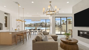 A modern living room with a large sofa, a dining area, and a kitchen. - Barefoot Beach Bungalow 9 Bedroom Home (St. George)