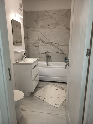 Un bagno con parete in marmo, lavandino, WC e vasca da bagno.