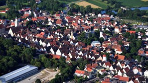 An aerial view of a densely packed village with traditional buildings, a prominent church, and a modern building with a flat roof. - Vacation apartment in Oettingen in Bavaria (Oettingen in Bayern)