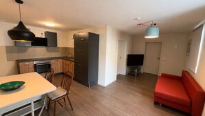 Et moderne køkken med spisebord og stole, en rød sofa og et fjernsyn i en opholdsstue.