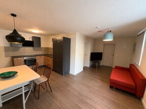 A modern kitchen with a dining table and chairs, a red sofa, and a TV in a living area. - Vacation apartment in Oettingen in Bavaria (Oettingen in Bayern)