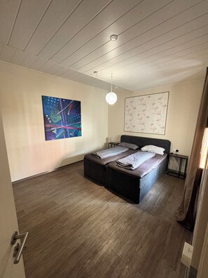 A bedroom with a bed, a nightstand, a wall art piece, and a ceiling light fixture. - Vacation apartment in Oettingen in Bavaria (Oettingen in Bayern)