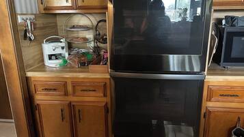 Una cocina con armarios de madera, un refrigerador de acero inoxidable y un microondas.