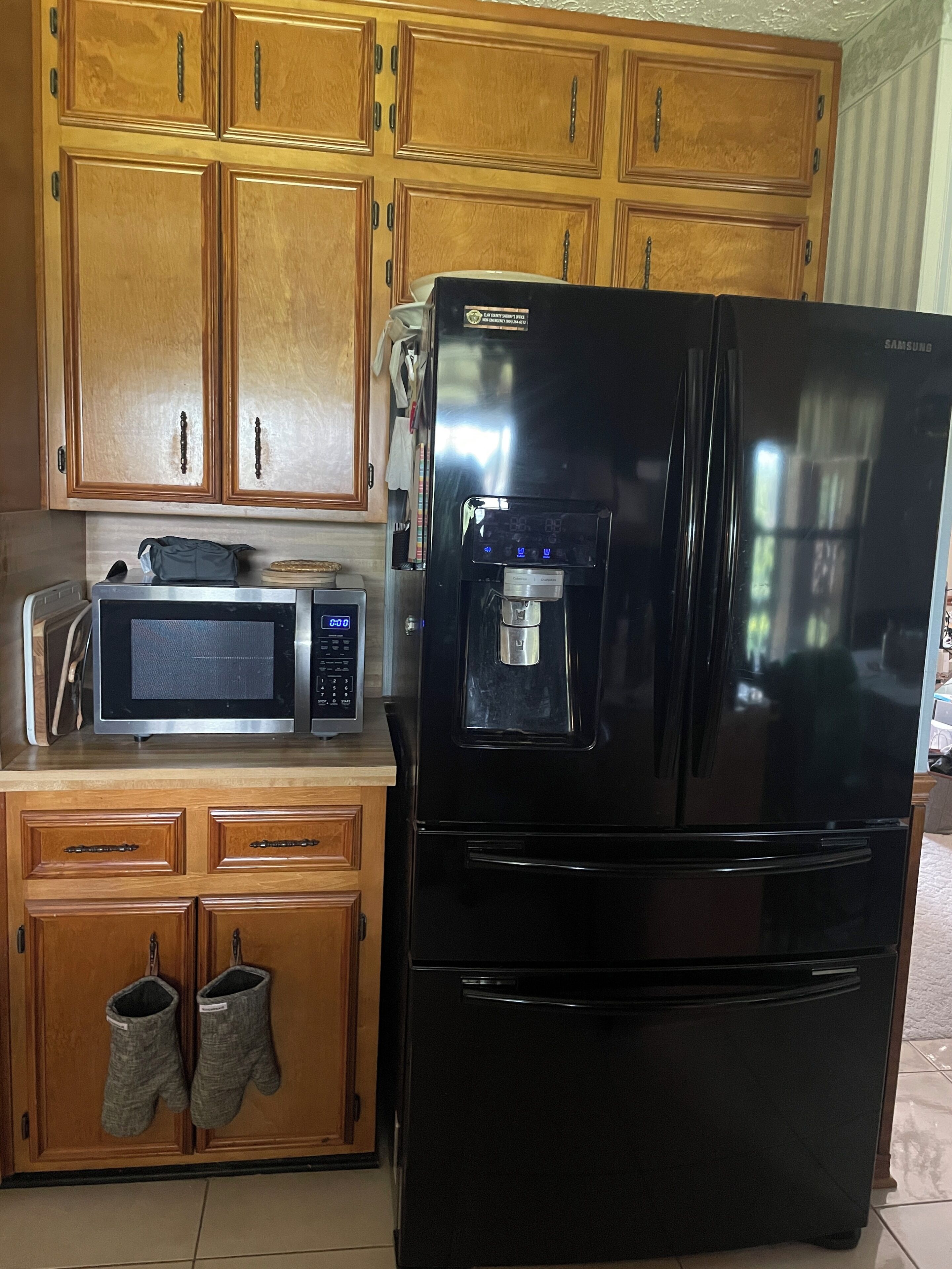A kitchen with wooden cabinets, a black refrigerator, a microwave, and a water dispenser.