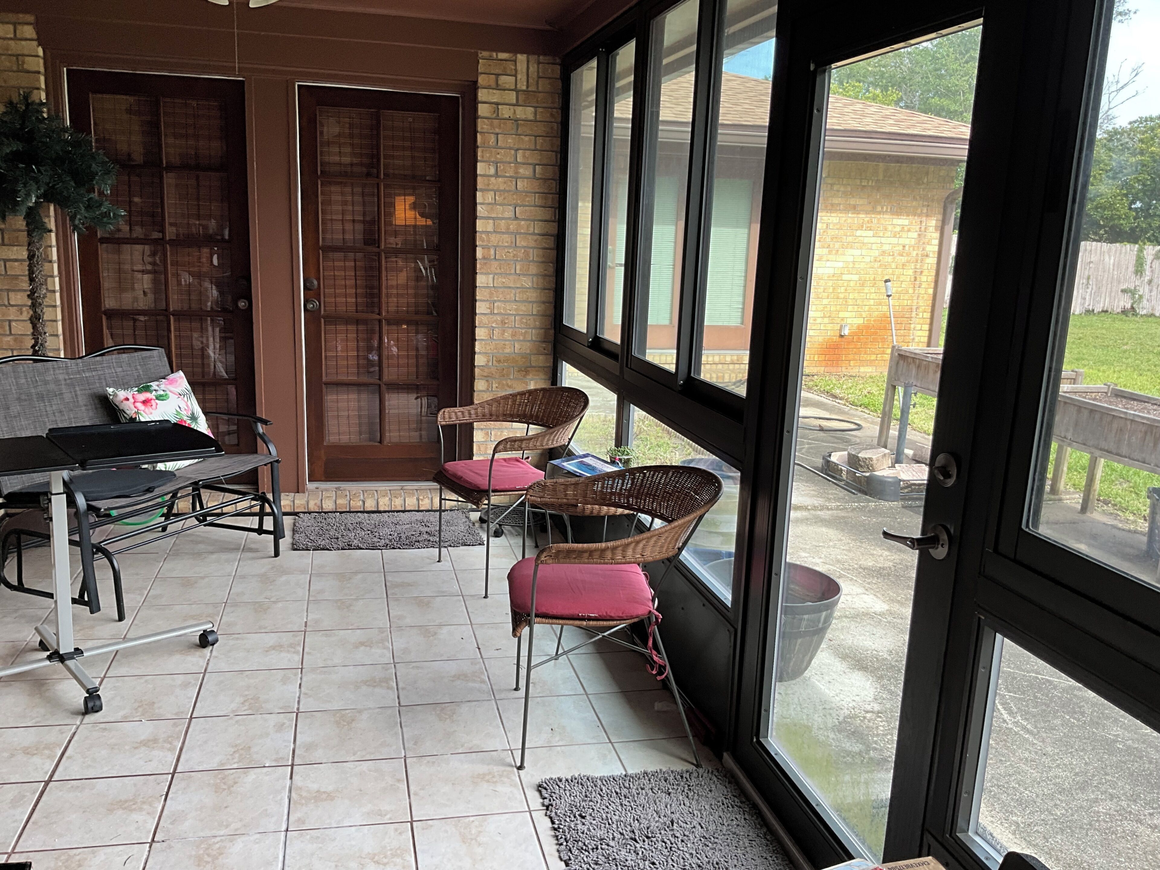 A covered patio with a seating area, a door, and a view of the backyard.