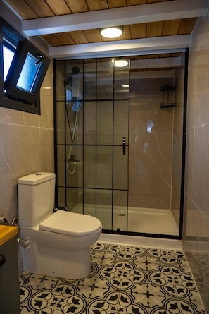 Un bagno con il water, cabina doccia e pavimento piastrellato.