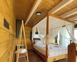 Un lit à baldaquin en bois, avec une literie blanche, une échelle en bois et une tête de lit en bois.