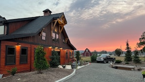 A large wooden house with a sloped roof, a garage, and a driveway leading to a parked truck. - Delightful 6-bedroom lodge in Monroe perfect for group getaways (Monroe)