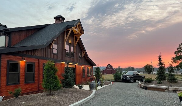 A large wooden house with a sloped roof, a garage, and a driveway leading to a parked truck. - Delightful 6-bedroom lodge in Monroe perfect for group getaways (Monroe)