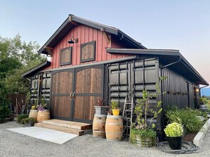 A rustic building with a red exterior, large wooden garage doors, and a sloped roof. - Delightful 6-bedroom lodge in Monroe perfect for group getaways (Monroe)
