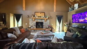 A cozy living room with a stone fireplace, leather sofas, and a flat-screen TV mounted on the wall. - Delightful 6-bedroom lodge in Monroe perfect for group getaways (Monroe)