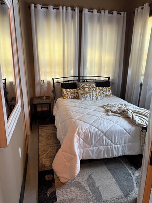 A bedroom with a bed, a nightstand, a lamp, and curtains. - Delightful 6-bedroom lodge in Monroe perfect for group getaways (Monroe)