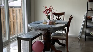 Un coin repas avec une table ronde, des chaises, un luminaire suspendu et une vue dégagée sur l’extérieur grâce à une grande fenêtre.