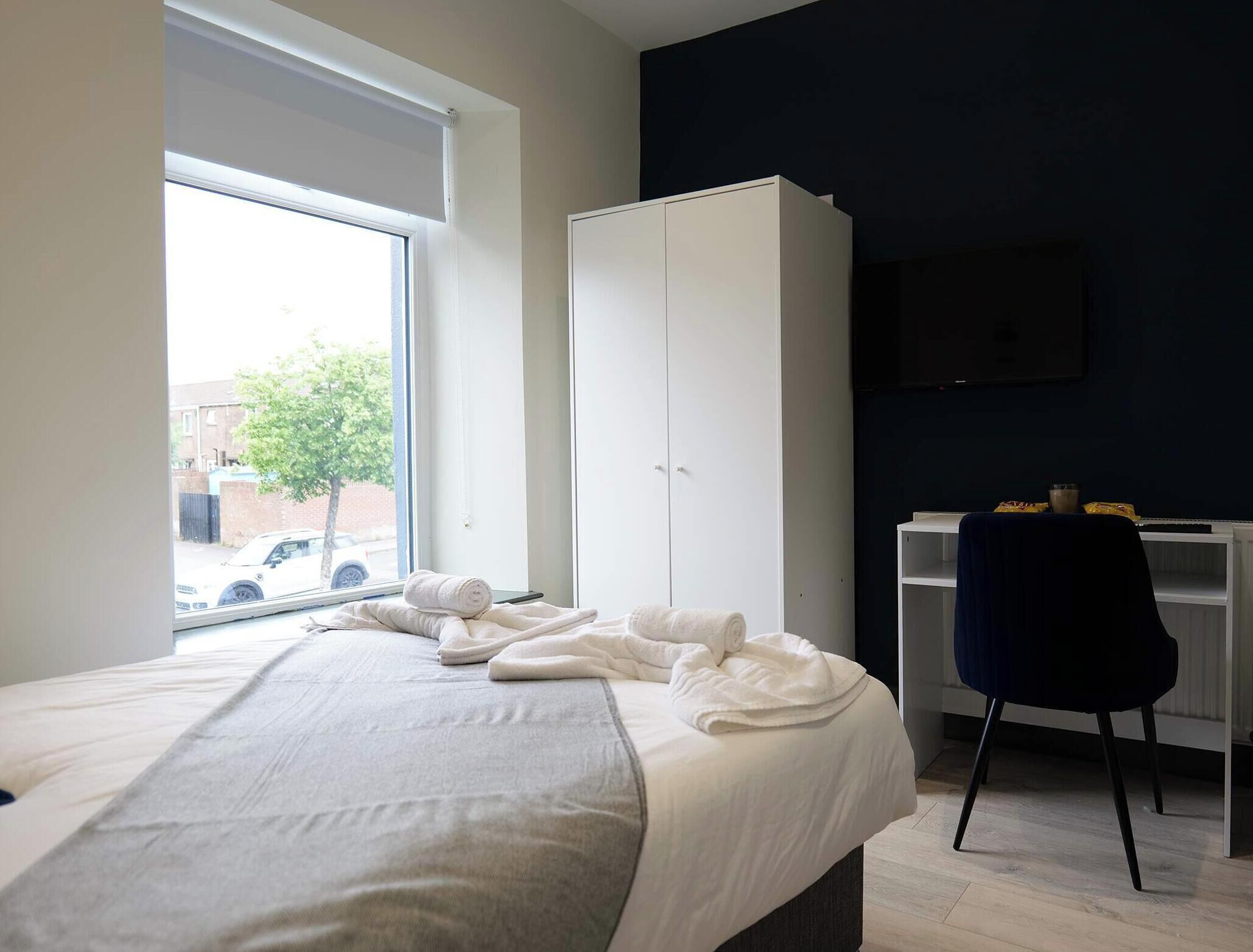 Une chambre à coucher avec un lit, une armoire, un bureau et un téléviseur.