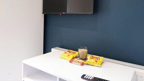 A room with a mounted TV, a white table with snacks and a remote control. - Private Double Room with Ensuite - Walk to City (Derry/Londonderry)