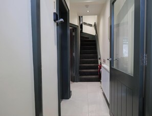 A hallway with a staircase, a fire extinguisher, and a door with a glass panel. - Private Double Room with Ensuite - Walk to City (Derry/Londonderry)
