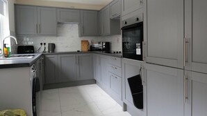 A compact kitchen with grey cabinets, a built-in oven, a microwave, and a sink. - Private Double Room with Ensuite - Walk to City (Derry/Londonderry)