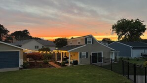 Un quartiere residenziale con case, un prato curato e un cielo al tramonto.