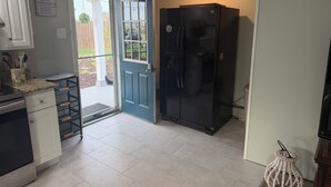 Una cucina con un frigorifero nero, mobili bianchi e una porta blu.