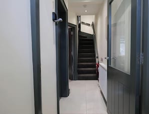 A hallway with a staircase, a fire extinguisher, and a door with a glass panel. - Private Double Room, Shared Bathroom-Walk to City (Derry/Londonderry)