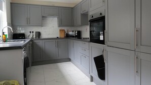 A compact kitchen with grey cabinets, a built-in oven, a microwave, and a sink. - Private Double Room, Shared Bathroom-Walk to City (Derry/Londonderry)