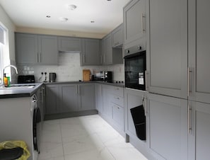 A compact kitchen with grey cabinets, a built-in oven, a microwave, and a sink. - Private Double Room, Shared Bathroom-Walk to City (Derry/Londonderry)
