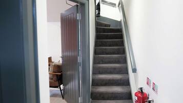 Eine Treppe mit Teppichstufen, ein Feuerlöscher und eine Tür zu einem anderen Raum.