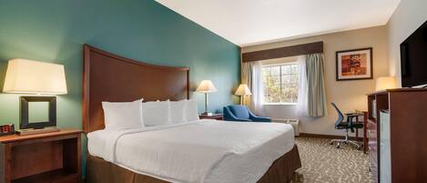A hotel room with a large bed, two bedside lamps, a desk with a chair, a TV, and a window with curtains.