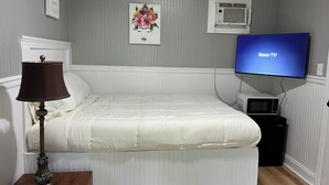 Une chambre à coucher avec un lit, une lampe, un téléviseur et un climatiseur fixé au mur.