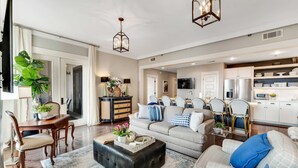 A spacious living room with a sofa, ottoman, and dining area. - Heron Walk, 30A Condo, Pool, Beach (Santa Rosa Beach)