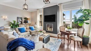 A living room with a fireplace, a television, and a dining area. - Heron Walk, 30A Condo, Pool, Beach (Santa Rosa Beach)