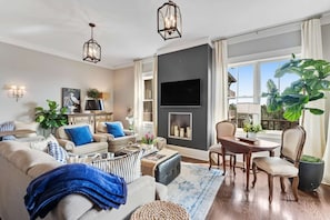 A living room with a fireplace, a television, and a dining area. - "Heron Walk" Blue Mountain Beach, 30A Condo, Pool, Beach Access (Santa Rosa Beach)