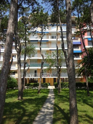 A multi-story building with balconies, surrounded by trees and a pathway. - Relaxing sea View Escape (Caorle)