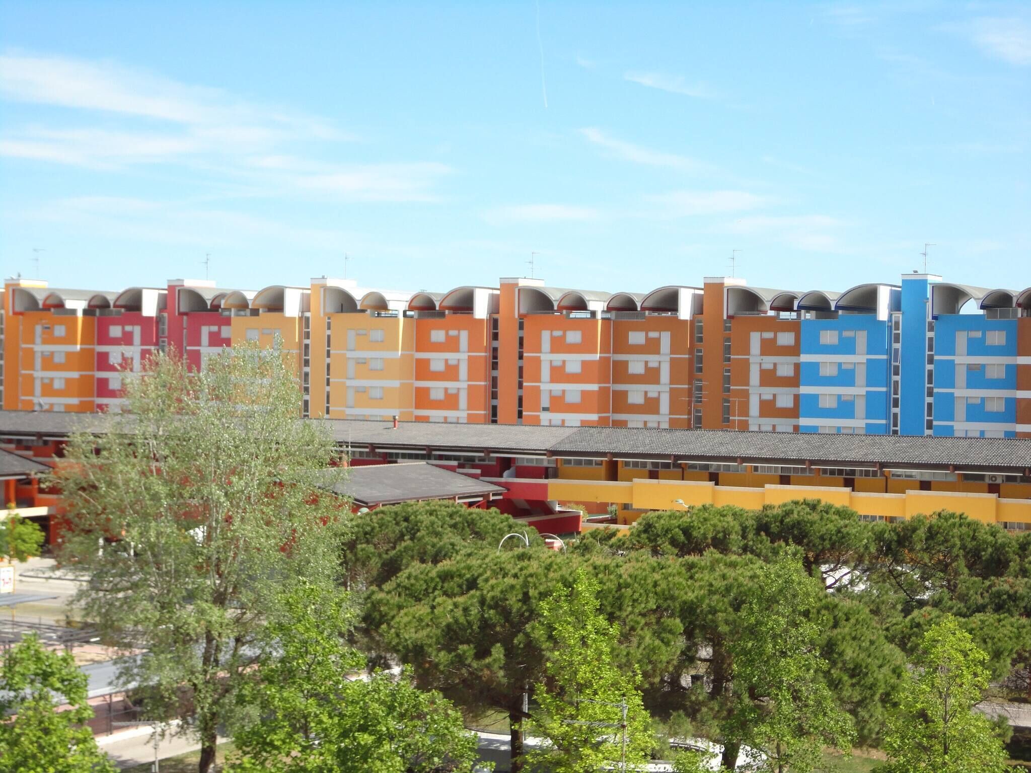 A row of colorful, modern apartment buildings with a flat roof and a uniform facade.