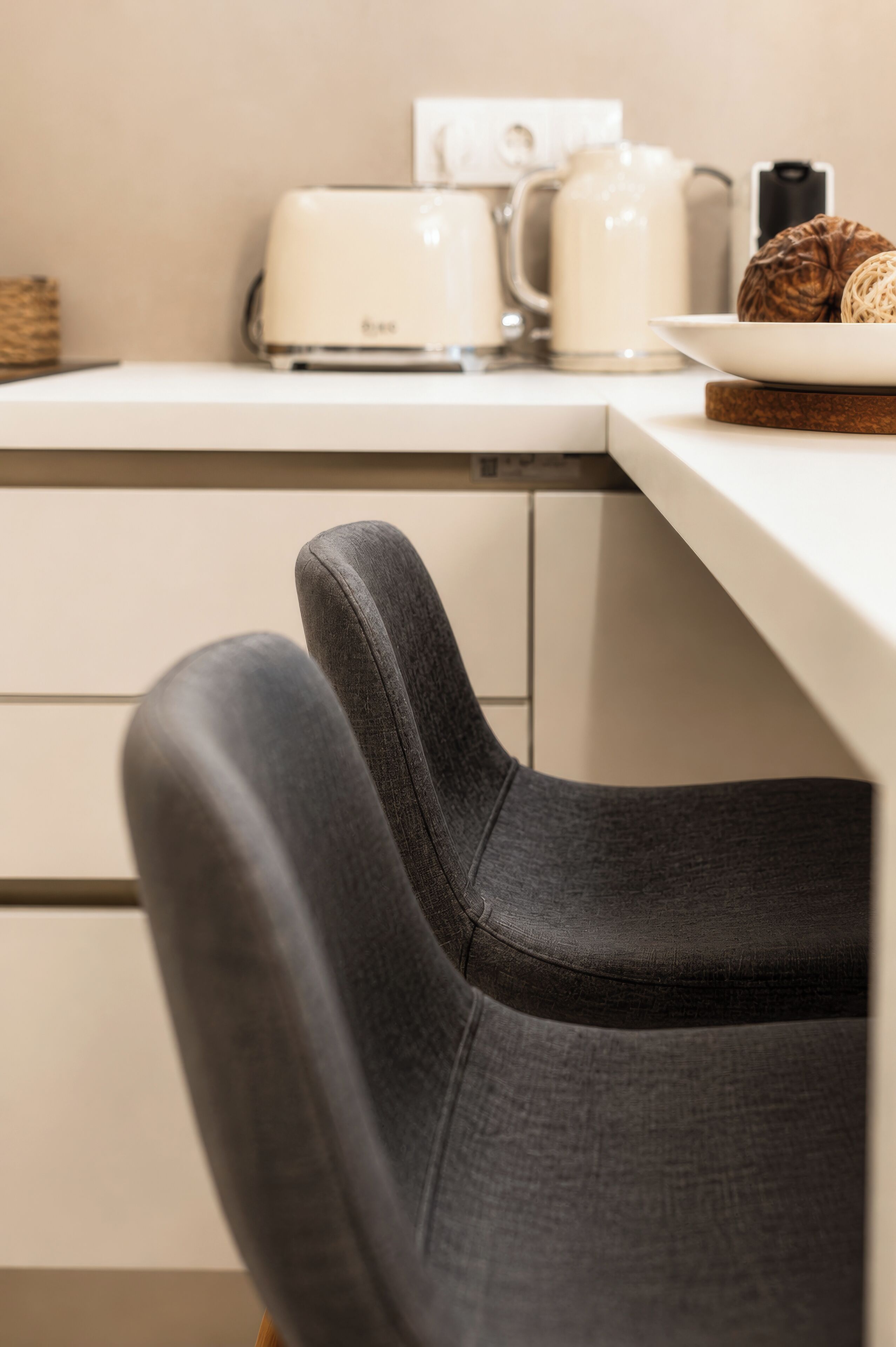 A kitchen area with a toaster, kettle, and a plate with a croissant.