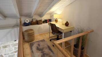A loft bedroom with a desk, chair, and a small plant.