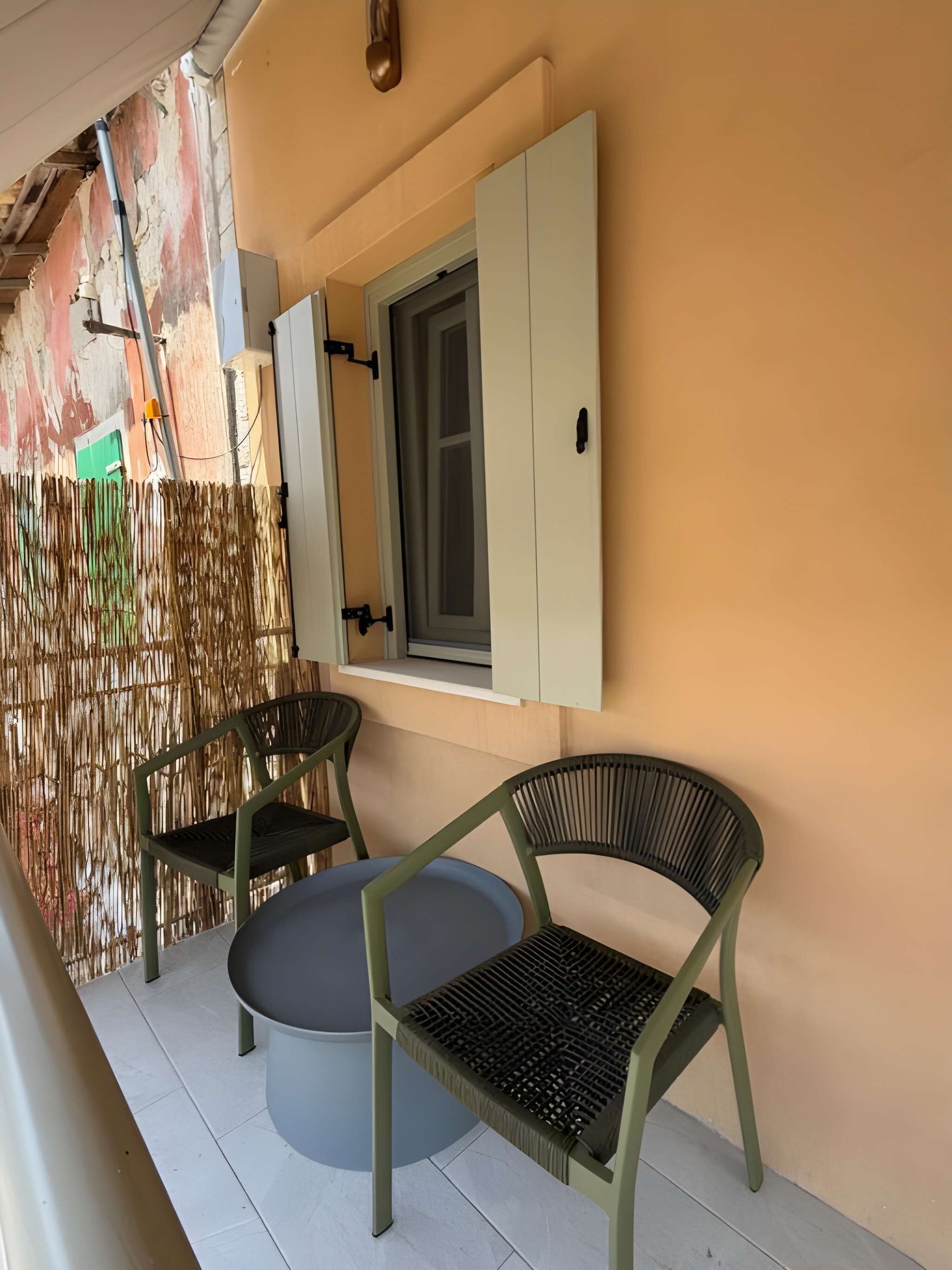 Una habitación con ventana, dos sillas, una mesa y una pared con textura.