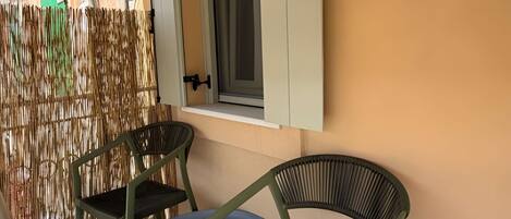 Una habitación con ventana, dos sillas, una mesa y una pared con textura.
