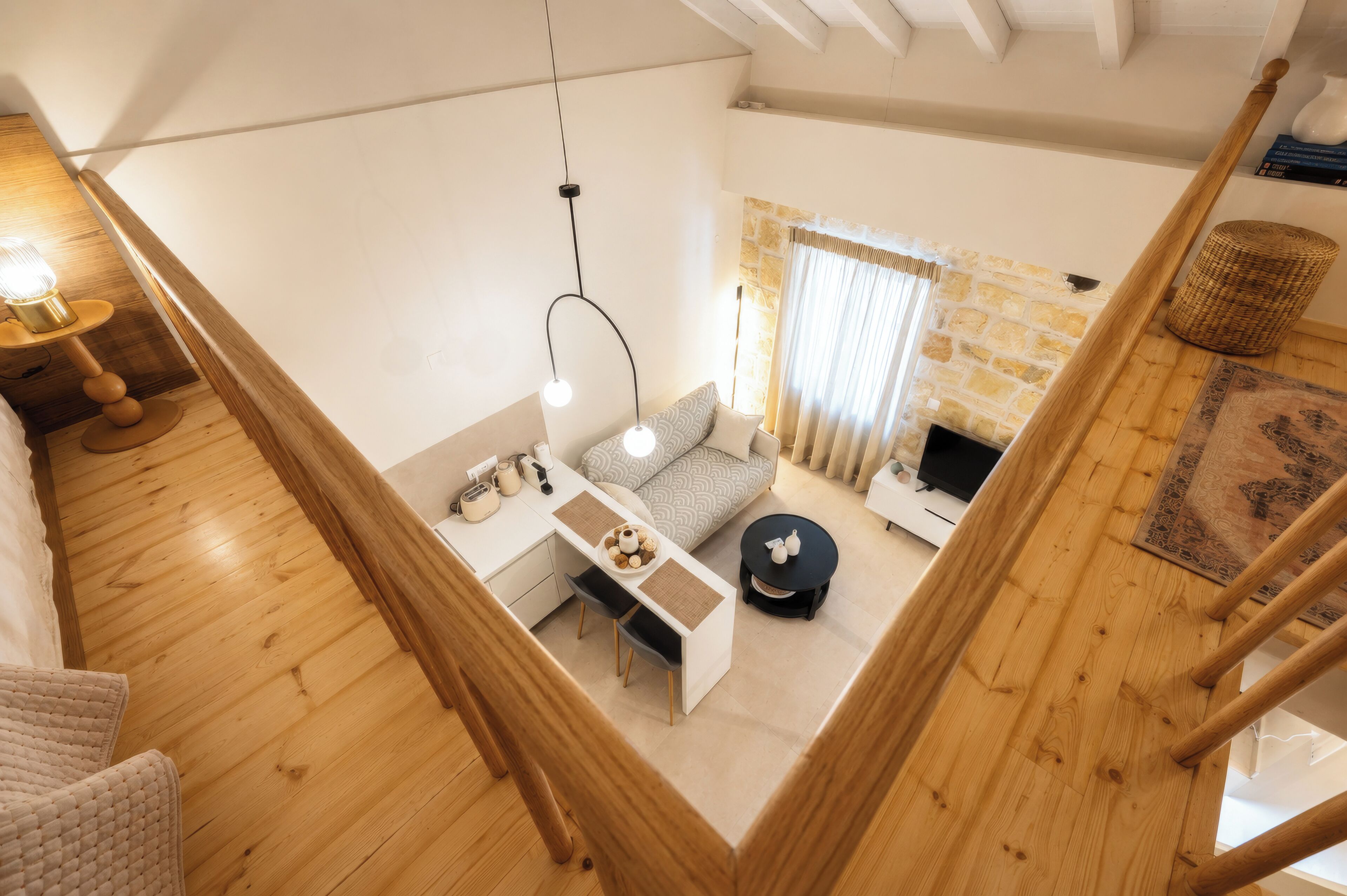 A modern living room with a wooden staircase, a sofa set, a dining table, and a fireplace.