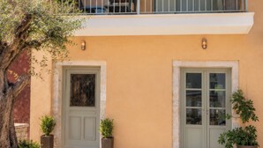 A two-story building with a balcony, a door, and potted plants. - Laena Apartment by All About Paxos (Gaios)