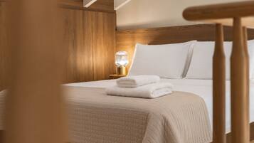 Una cama bien hecha con una colcha acolchada, una lámpara de noche y un cabecero de madera.