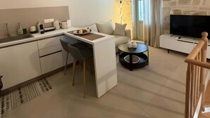 A modern living space with a kitchen, dining area, and a stone fireplace. - Laena Apartment by All About Paxos (Gaios)