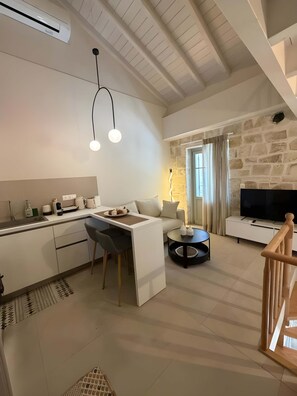 A modern living space with a kitchen, dining area, and a stone fireplace. - Laena Apartment by All About Paxos (Gaios)