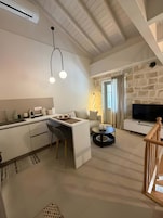 A modern living space with a kitchen, dining area, and a stone fireplace.