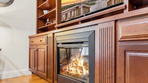 Una chimenea con frente de vidrio, armarios de madera y un estante superior.